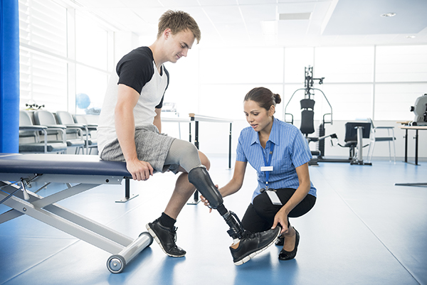 Female physiotherapist helping young man with prosthetic leg